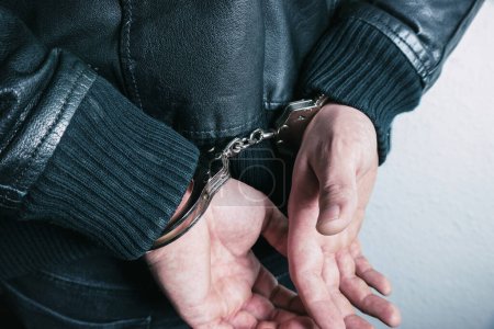 Criminal hands locked in handcuffs