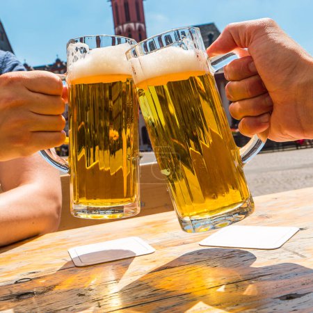 Foto de Dos manos tintineando vasos de cerveza en verano - Imagen libre de derechos