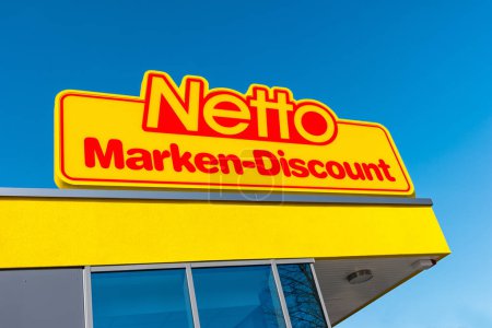 Téléchargez les photos : AACHEN, ALLEMAGNE FÉVRIER 2017 : Netto discount store against blue sky. Il fait partie du groupe Edeka, la plus grande société de supermarchés allemande employant 250 000 personnes.. - en image libre de droit