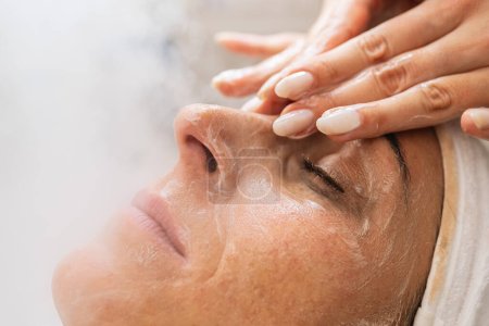 Téléchargez les photos : Femme heureuse a traitement de beauté du visage avec vapeur faciale ozone et massage dans le salon de beauté. - en image libre de droit