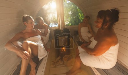 Photo for Happy girlfriends relaxing at the wooden barrel sauna in norway. - Royalty Free Image