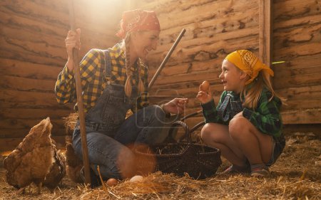 Photo for Proud chicken farmer woman and her daughter showing the organic eggs of her hens produced in a henhouse - Royalty Free Image