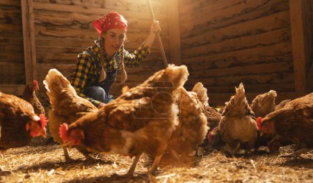Photo for Proud chicken farmer woman takes care of her chickens in a henhouse - Royalty Free Image
