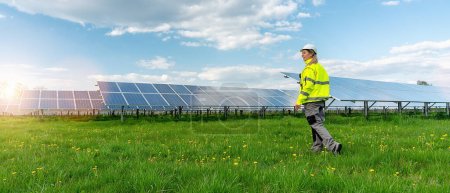 Photo for Female engineer walking in front of a Solar Park. Sustainable energy and solar power field concept image - Royalty Free Image