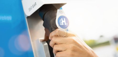 Foto de La mujer sostiene un dispensador de combustible con el logotipo de hidrógeno en la gasolinera. motor de combustión h2 para la imagen concepto de transporte ecológico libre de emisiones - Imagen libre de derechos