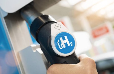 Foto de El hombre sostiene un dispensador de combustible con el logotipo de hidrógeno en la gasolinera. motor de combustión h2 para la imagen concepto de transporte ecológico libre de emisiones - Imagen libre de derechos
