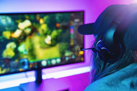 Photo for Female Gamer plays strategy Online Video Game on her Personal Computer. Room Lit by Neon Lights in Retro Arcade Style. Online Cyber e-Sport Internet Championship. - Royalty Free Image