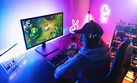 Photo for Professional female Gamer pointing and Playing in First-Person Shooter Online Video Game on her Personal Computer. Room Lit by Neon Lights in Retro Arcade Style. Online Cyber e-Sport Championship - Royalty Free Image