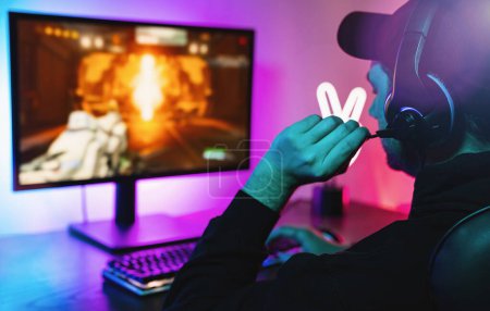 Photo for Young gamer playing video games online First-Person Shooter while broadcasting on social media - Working live streaming on internet platforms - Royalty Free Image