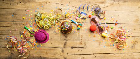 Téléchargez les photos : Donuts de carnaval d'Allemagne avec sucre glace sur une surface en bois clair avec des confettis et des banderoles dessus - fond pour une fête de carnaval ou des parties - en image libre de droit