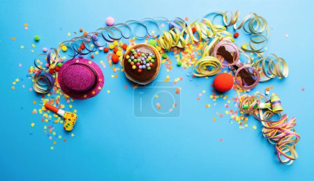 Téléchargez les photos : Krapfen, berliner ou beignet de carnaval d'Allemagne avec sucre glace sur fond bleu, copiez l'espace avec des confettis et des banderoles dessus - fond pour une ou plusieurs fêtes de carnaval - en image libre de droit