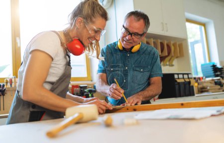 Dos carpinteros que marcan medidas sobre madera en un taller de carpintería