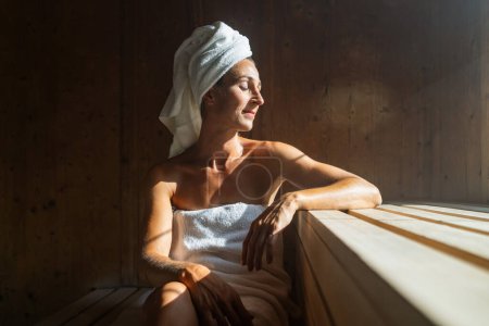 Foto de Mujer mayor sentada relajada en una sauna de madera - Imagen libre de derechos