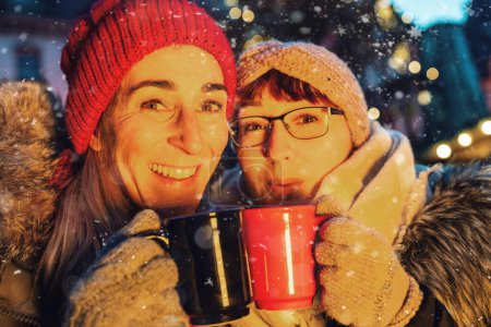 Téléchargez les photos : Amis boire chaud vin chaud chaud chaud ou punch à un marché de Noël - en image libre de droit