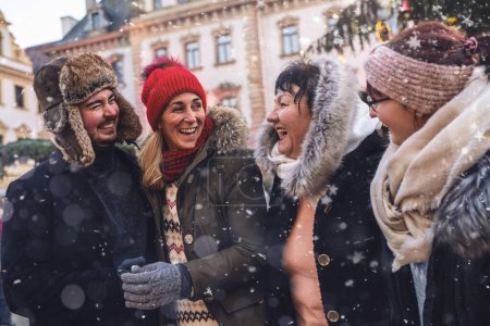 Téléchargez les photos : Ami joyeux partageant un rire dans un marché de Noël enneigé - en image libre de droit