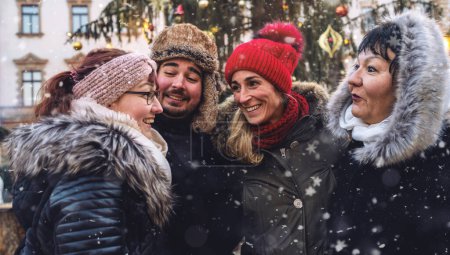 Téléchargez les photos : Heureux amis réunis à un marché de Noël festif dans la neige - en image libre de droit