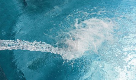 Flux d'eau frappant la surface d'une piscine créant des bulles et des ondulations