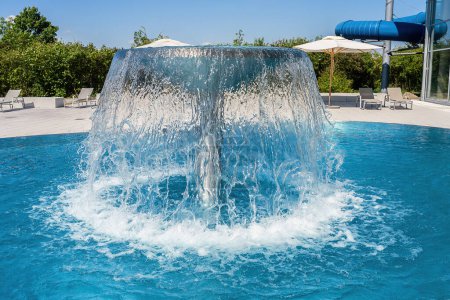 Waterfall mushroom feature in a swimming pool creating a large splash for fun in a spa resort