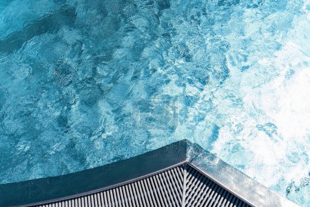 Overhead view of pool corner with textured blue water and grating edge