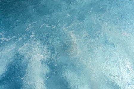 Agua de piscina azul remolino con reflejos de luz y suaves ondulaciones