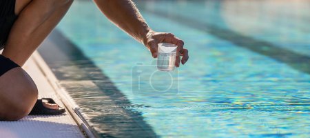 Hand hält einen kleinen Behälter, um eine Wasserprobe aus einem Schwimmbad in einem Hotel zu entnehmen