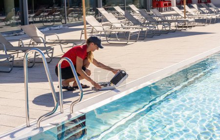 Rettungsschwimmer kniet am Pool mit Wassertest-Set
