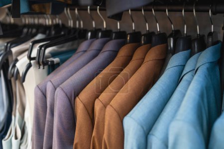 Close-up of assorted suits on hangers, focused on texture and colors at a men's clothing store