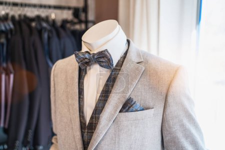 Mannequin dressed in a light gray suit with a plaid bow tie and matching pocket square