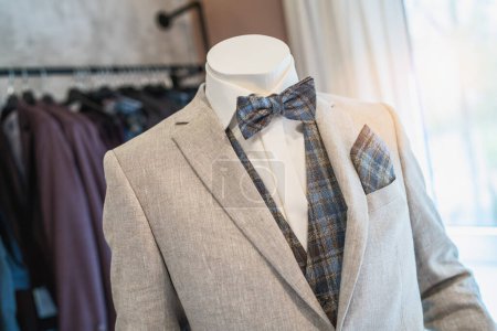Mannequin dressed in a light gray suit with a plaid bow tie and matching pocket square at a wedding store