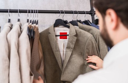 Homme parcourant diverses vestes de costume sur un rack dans un magasin