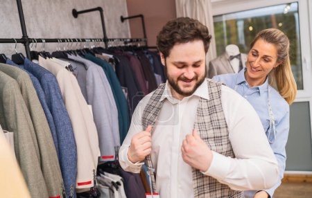 Cliente probándose una chaqueta a cuadros con sastre asistiendo en una boutique