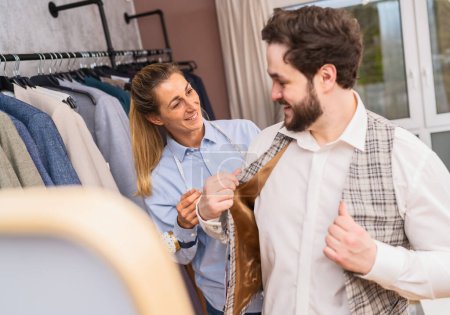 Foto de Adaptar el ajuste de una chaqueta a cuadros en un cliente en una boutique - Imagen libre de derechos