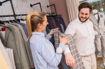 Tailor helping a client try on a checkered jacket in a clothing boutique
