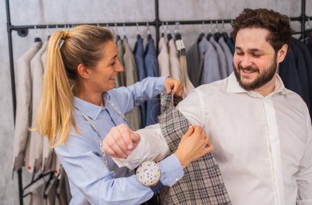 Tailor adjusting a checkered vest on a smiling client in a suit shop