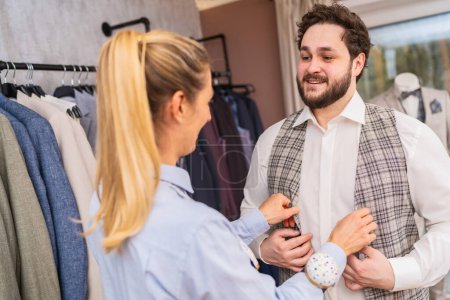 Tailor adjusting a waistcoat on a smiling client in a clothing boutique