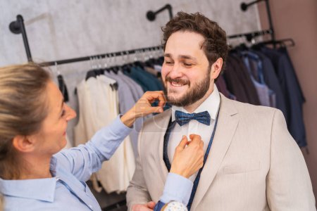 Tailor adjusting a tie for a happy client in a suit boutique