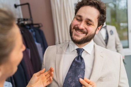 homme heureux dans un costume étant équipé pour une cravate par un tailleur