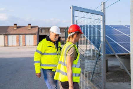 Téléchargez les photos : Ingénieurs masculins et féminins à la porte d'une centrale solaire pour l'inspection - en image libre de droit