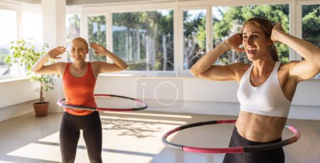 Photo for Woman doing hula hoop during an exercise class in a gym. Healthy sports lifestyle, Fitness, Healthy concept. - Royalty Free Image