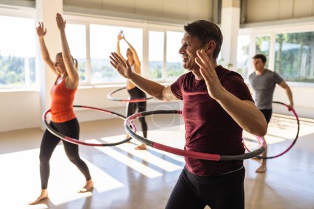Photo for Team Sport women and men doing hula hoop in step waist hooping forward stance in fitness gym for healthy lifestyle concept. - Royalty Free Image
