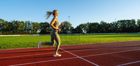 Foto de Atleta corriendo en un campo soleado - Imagen libre de derechos