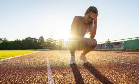 Photo for Distressed female athlete resting on a running track - Royalty Free Image