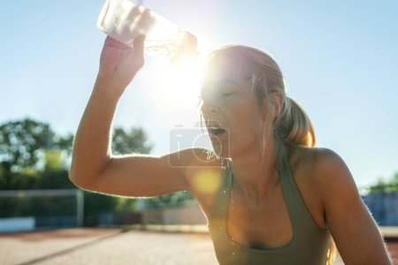 Foto de Mujer que vierte el agua en la cara después del entrenamiento, la erupción solar, la botella de deportes, refrescante - Imagen libre de derechos