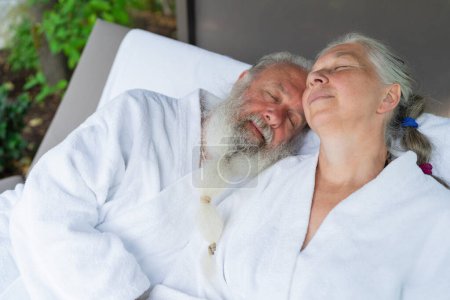 Schöner alter Mann und attraktive alte Frau relaxen zusammen auf Liegestühlen im Wellness-Kurort. Senior Moments Konzeptbild