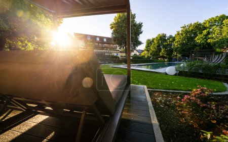 Coucher de soleil depuis une chaise longue au bord de la piscine dans un jardin paysager