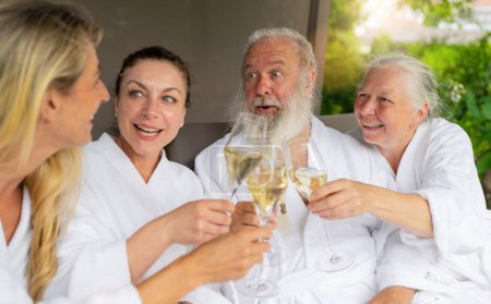 Two women and a senior couple laughing and toasting with champagne glasses at a spa wellnes hotel