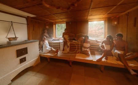 Die Menschen entspannen gemeinsam in der heißen finnischen Sauna. Dramatisches Licht mit Dampf-, Spa- und Wellness-Konzept.