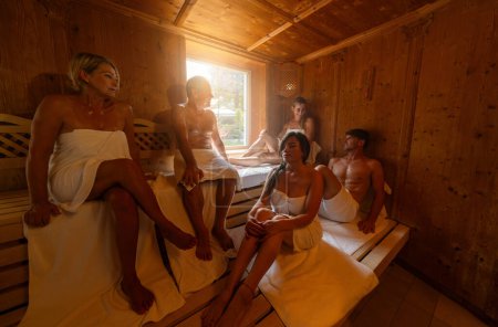 Personas sentadas en una sauna, algunas hablando y relajándose juntas en la sauna finlandesa caliente. luz dramática con el concepto de vapor, spa y bienestar.