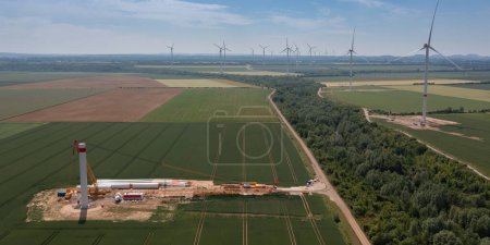 Vista aérea de un sitio de construcción de aerogeneradores entre campos agrícolas verdes