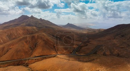 Desert landscape of Fuerteventura, Canary Islands, with winding road and ocean in the distance